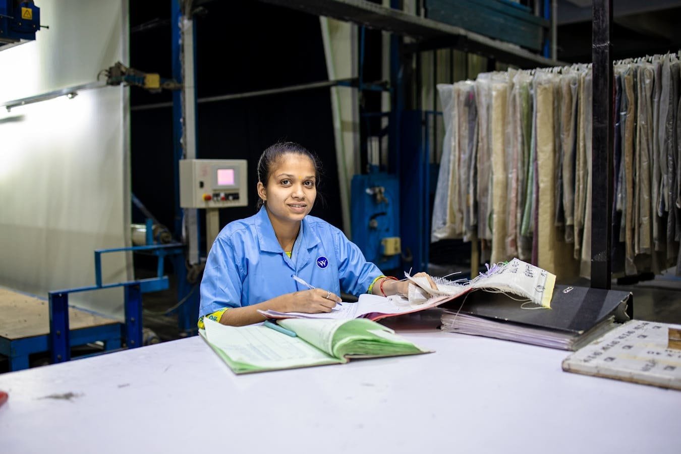 Estabilidade do Servidor Público: Quando É Adquirida 1 Female textile worker in factory reviewing documents at a desk.