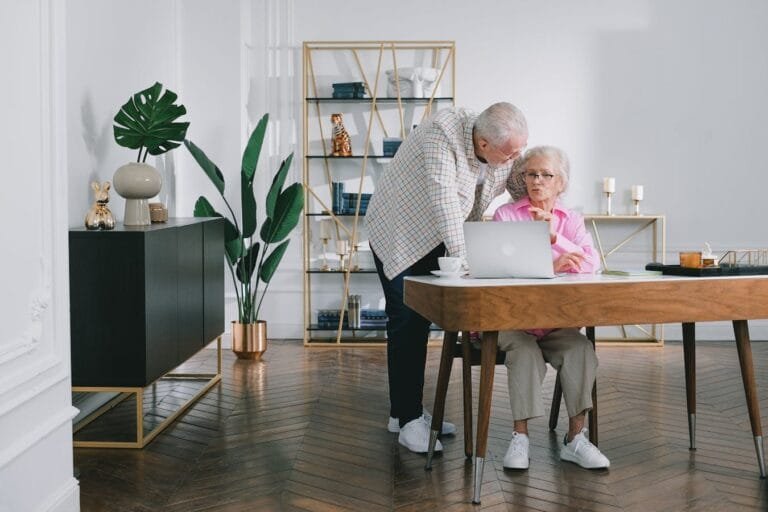 Senior couple using a laptop while discussing something in their modern living room.