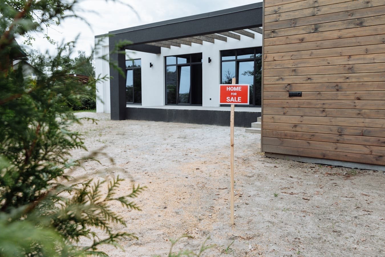 Modern house exterior with a Home for Sale sign in front yard.