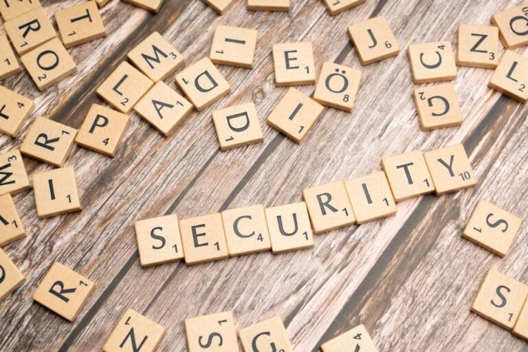 Wooden letter tiles form the word Security amidst scattered tiles on wood.