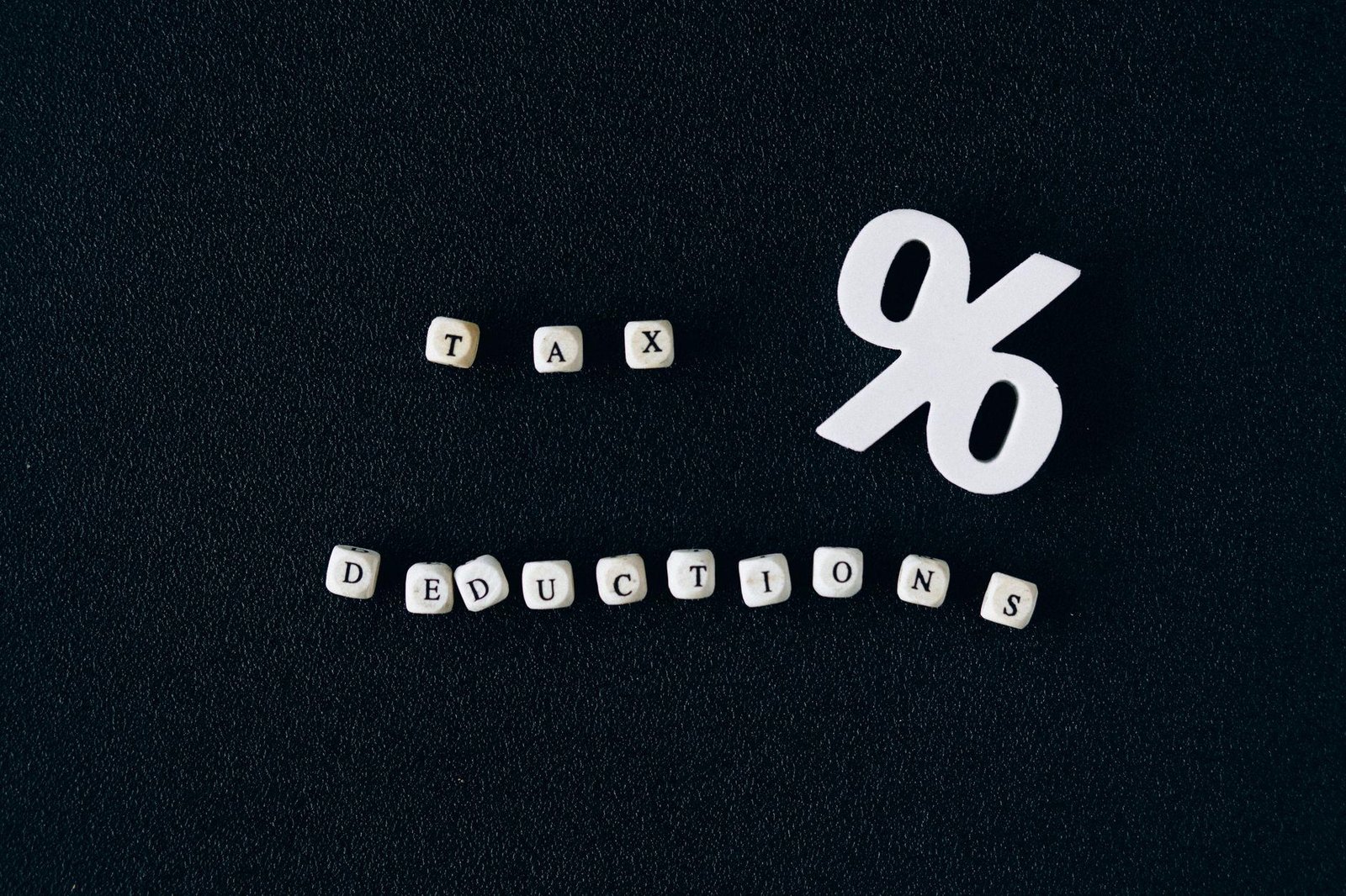 Conceptual image of tax deductions with alphabet blocks and percent symbol on black surfac