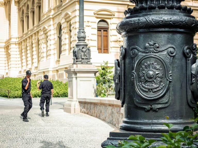 Ação Popular: Proteção do Patrimônio Público pelo Cidadão 5 Two security guards patrol in front of ornate historic architecture in São Paulo, Brazil.
