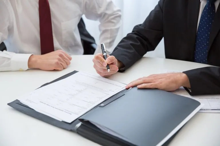 Acordo de não persecução cível na improbidade: condições e vantagens da negociação 15 Two professionals signing a contract at a business meeting in an office.