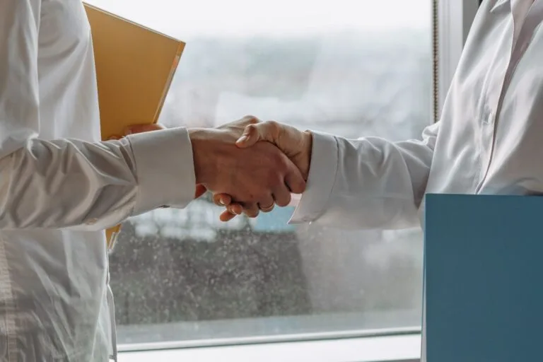 Two business professionals shaking hands indoors, symbolizing agreement.