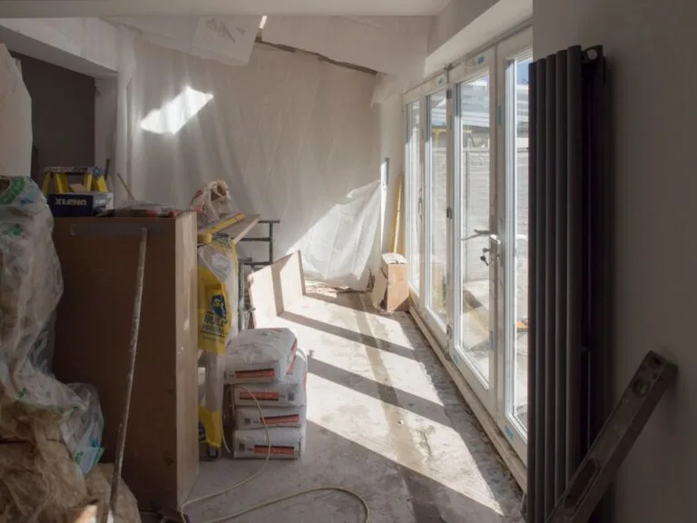 A construction area featuring renovation work in progress with large windows bringing in natural light.