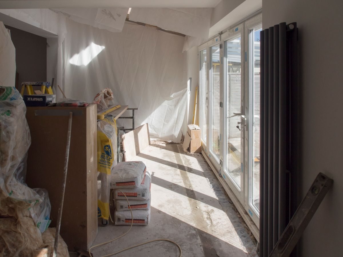 Aditivos contratuais: limites para alterar prazo, valor e objeto do contrato 1 A construction area featuring renovation work in progress with large windows bringing in natural light.