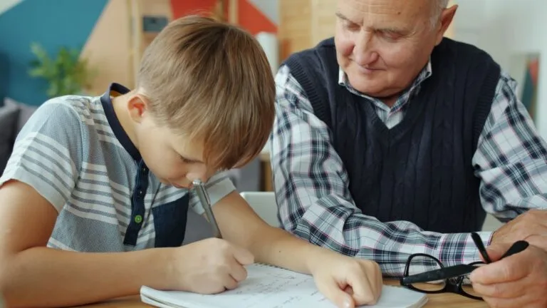 Alimentos entre cônjuges e para os pais: além da pensão para os filhos 6 Elderly man assisting young boy with homework, fostering learning and bonding.