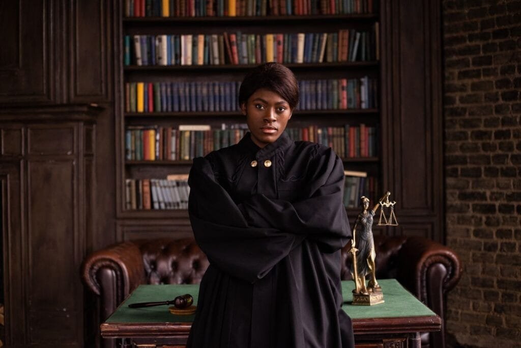 Recebi alta do auxílio por incapacidade, mas ainda não consigo trabalhar. E normal? 1 A confident female judge in a formal robe posing in a classic legal library setting.