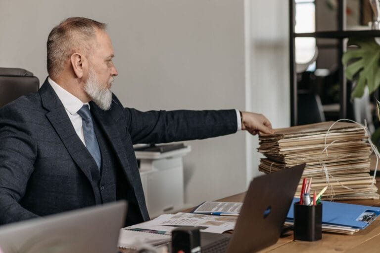 Aposentadoria do trabalhador rural: carência, idade reduzida e prova do labor 7 Mature businessman reaching for a stack of files on his desk in a modern office environmen