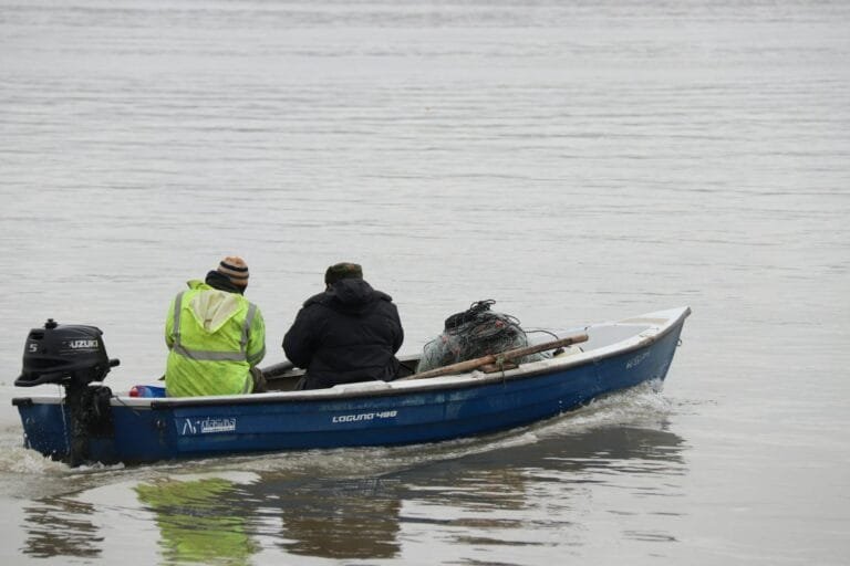 Pescadores artesanais em barco com redes de pesca, atividade com direito à aposentadoria do pescador artesanal