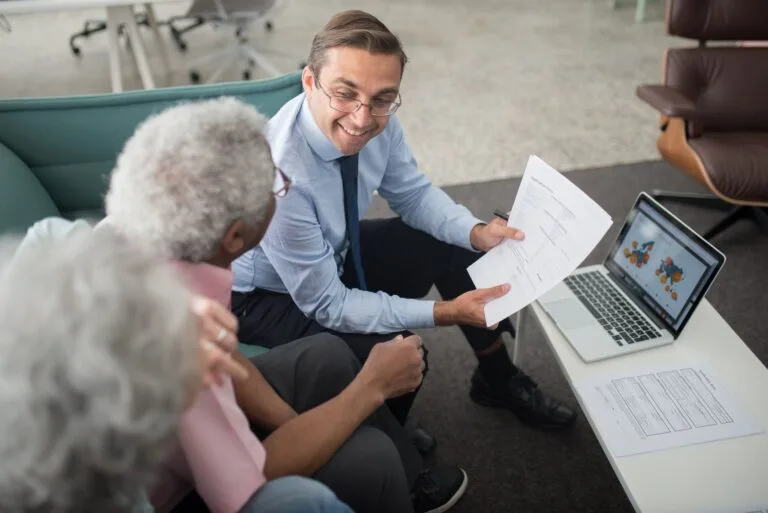 Financial advisor discussing documents with senior clients in an office setting, showcasin