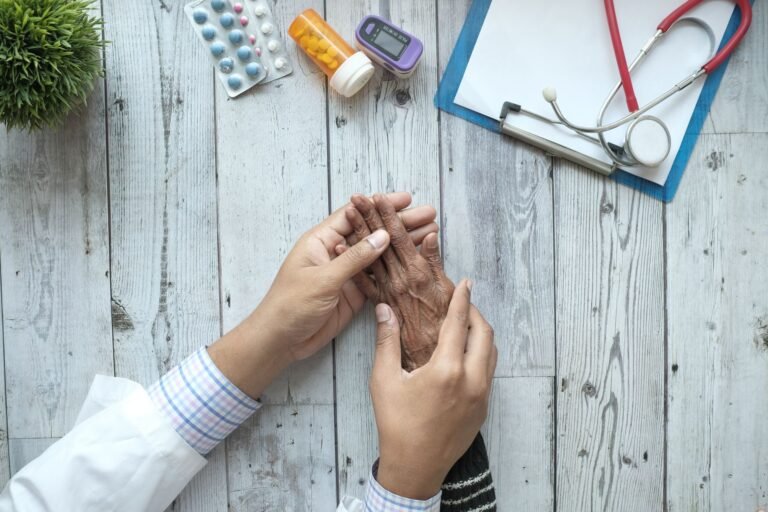 Aposentadoria por Incapacidade Permanente: Quando o INSS Concede 3 A doctor holding an elderly patient's hands on a desk with medication and stethoscope.