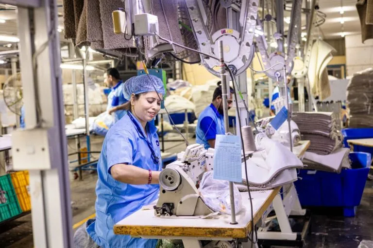 Close-up of textile factory workers operating sewing machines in an industrial setting.
