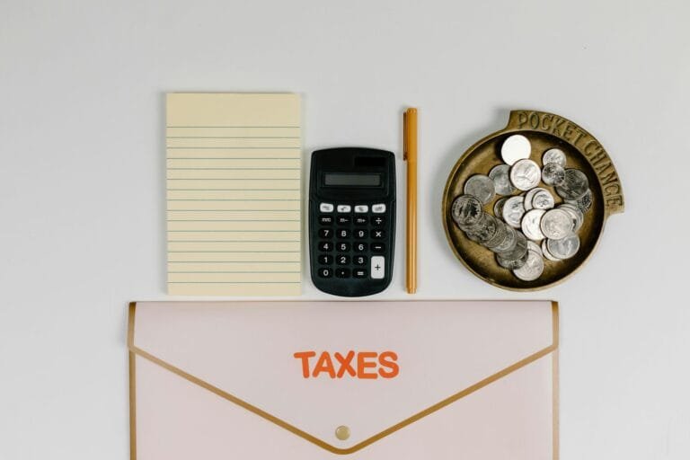A flat lay of tax preparation essentials: calculator, coins, notepad, pen, and folder.