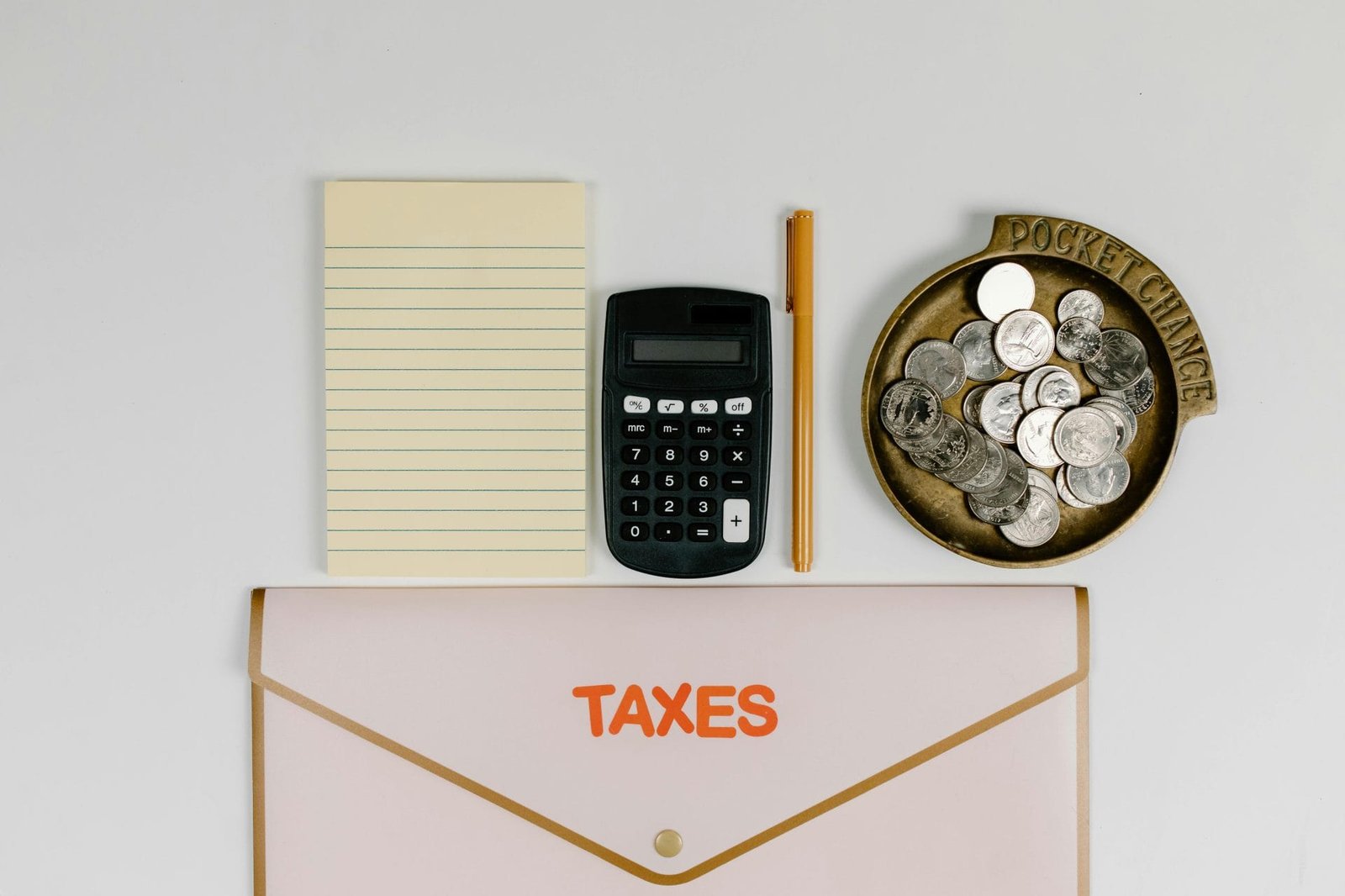 Auto de Infração: Como Impugnar Administrativamente 1 A flat lay of tax preparation essentials: calculator, coins, notepad, pen, and folder.