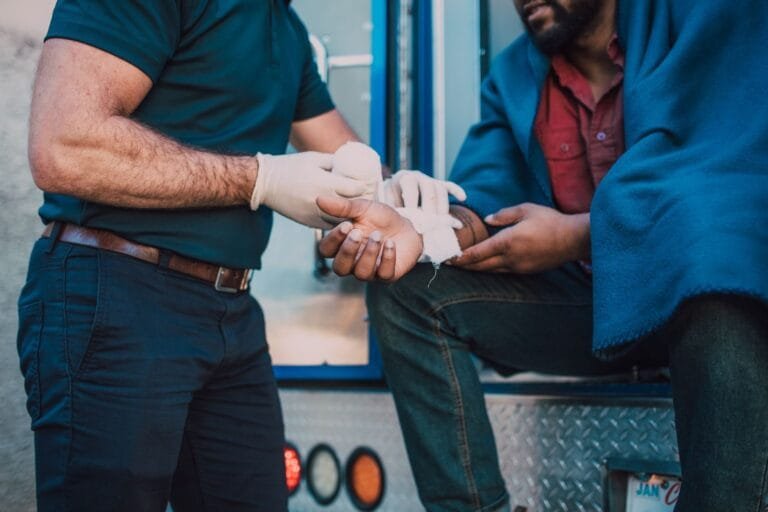 Paramedic offers first aid to an injured person near an ambulance.