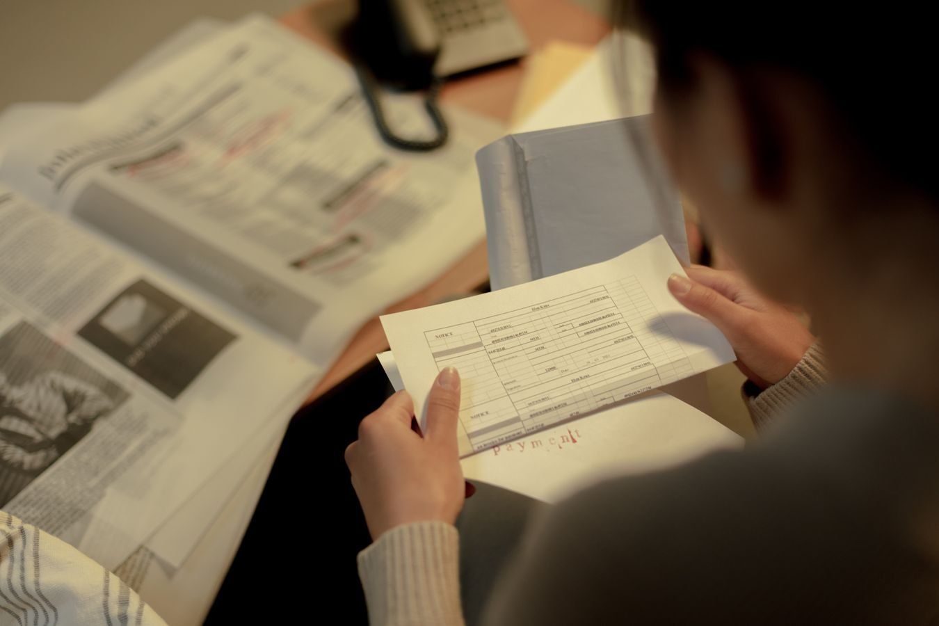 Averbacao de tempo: como aproveitar contribuicoes de regimes diferentes 1 Adult woman reading a questionnaire and job postings indoors at a table, focused and contemplative.