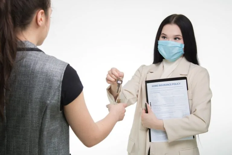 Real estate agent in a face mask hands keys to a client, illustrating safe business practi
