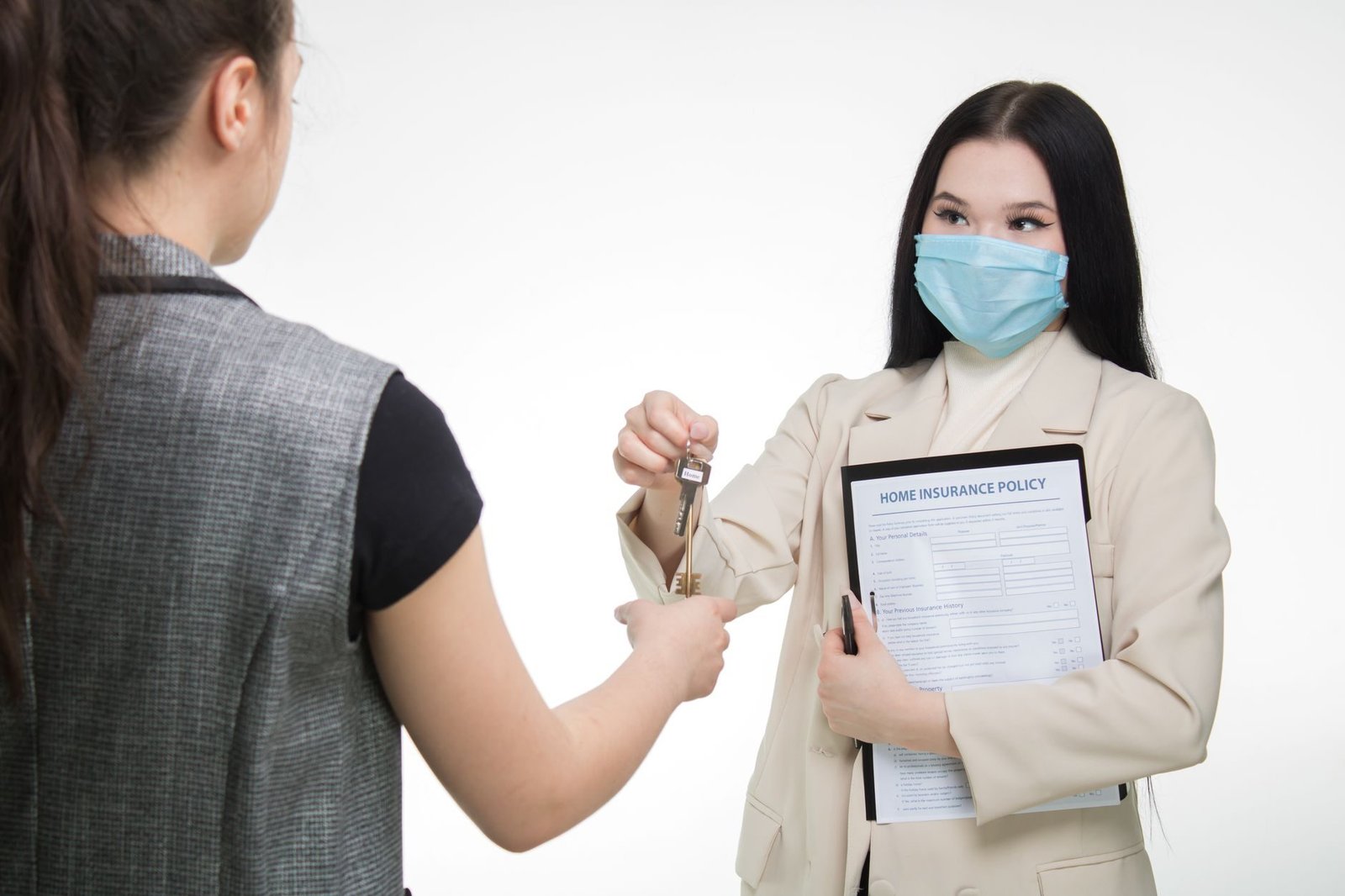 Real estate agent in a face mask hands keys to a client, illustrating safe business practi