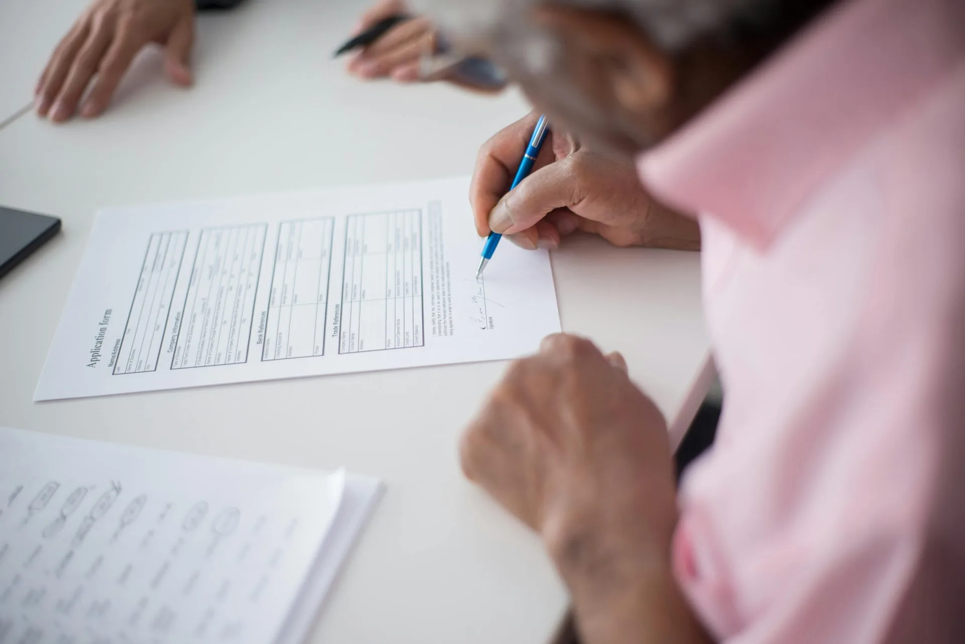 Benefícios do INSS 2026: Lista Completa com Códigos e Requisitos 1 Elderly man signing important business document at desk in office setting.