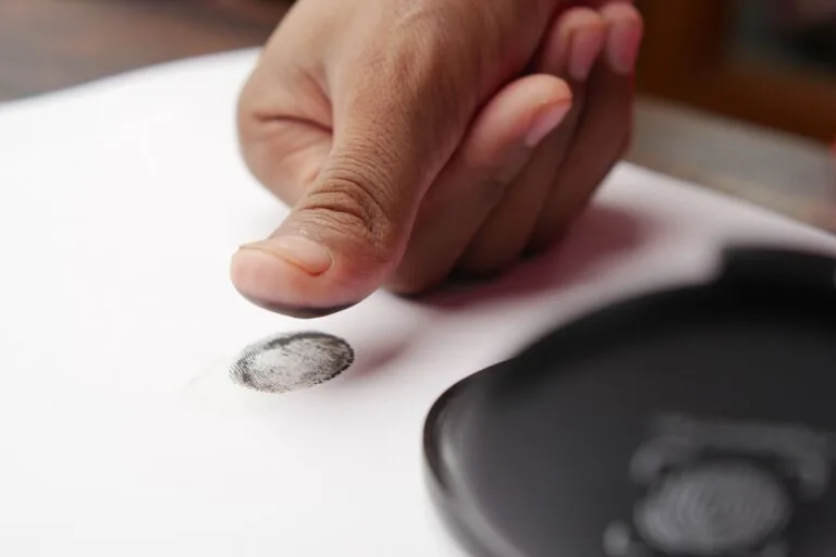 Biometria no INSS: quais documentos comprovam o registro 3 Detailed shot of a thumb creating a fingerprint on white paper, ideal for security themes.