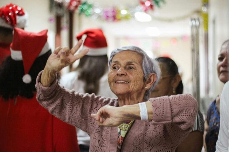 Joyful elderly woman celebrating indoors during a festive Christmas event.