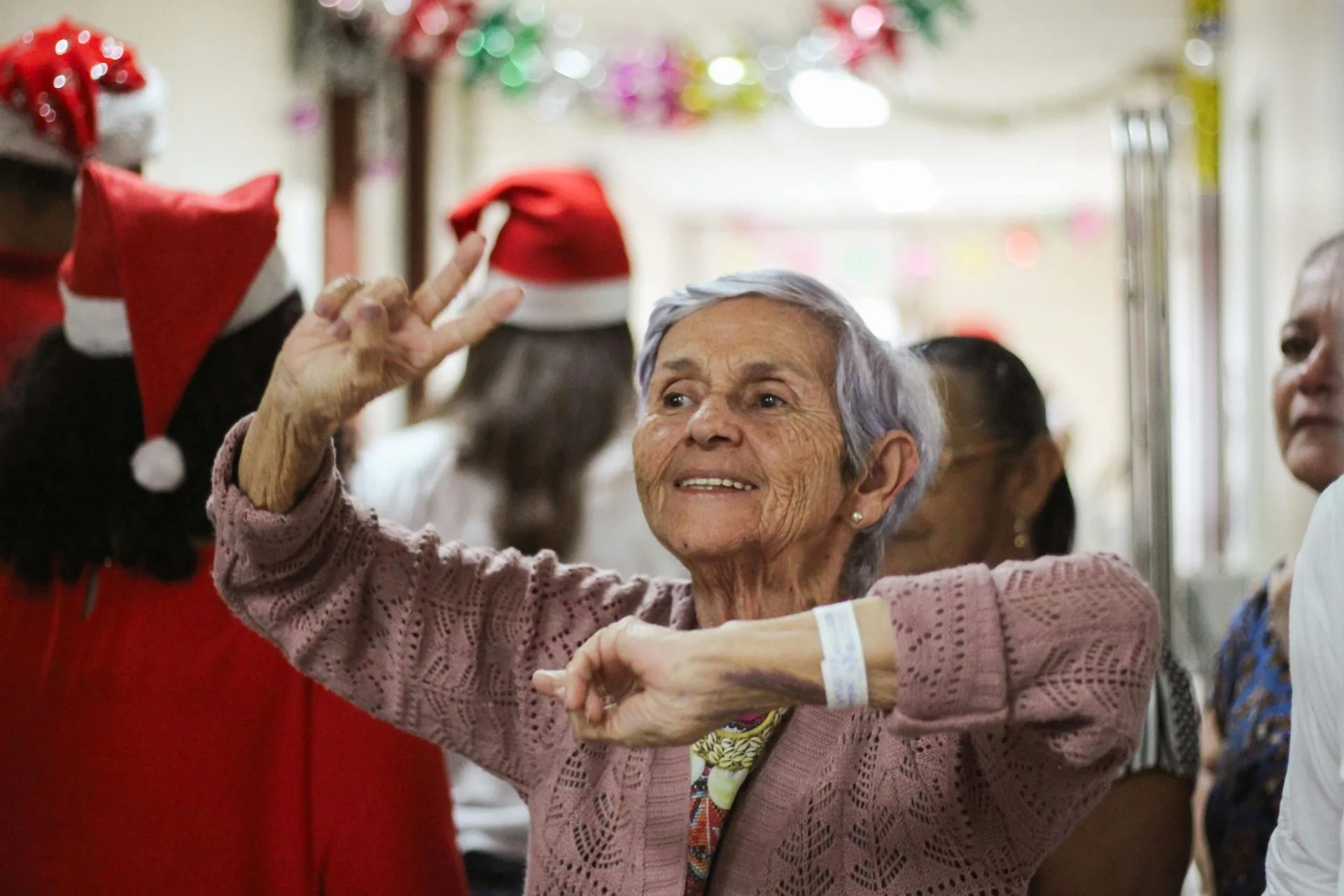 BPC Sem Contribuição: Mitos e Verdades Sobre o LOAS 2026 1 Joyful elderly woman celebrating indoors during a festive Christmas event.
