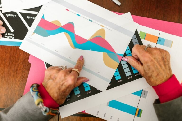 Senior adult pointing at colorful business graphs with data analysis documents on a wooden