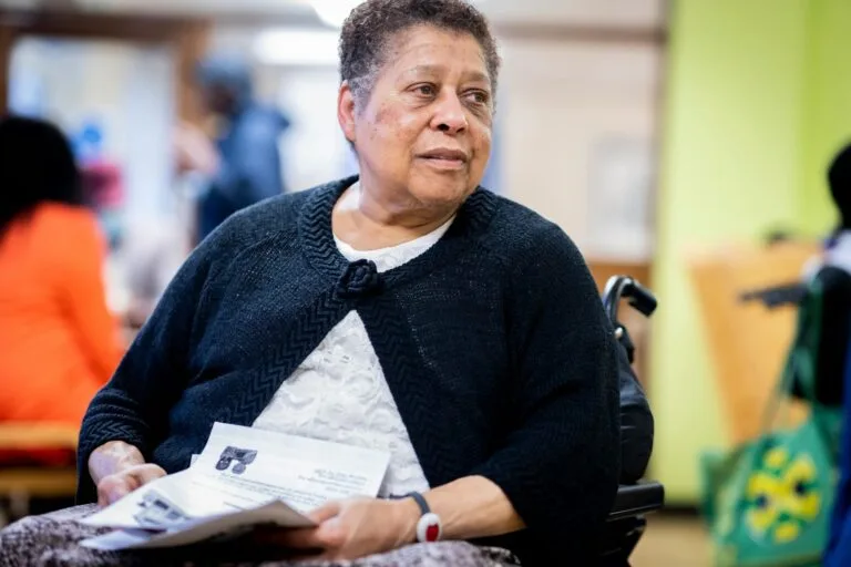BPC: INSS Antecipa Perícias para Deficientes em SP 6 A thoughtful senior African American woman holding documents, sitting in a wheelchair indoors.