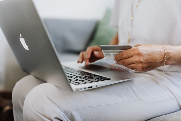 Cláusula penal nos contratos: limites da multa e como negociá-la 2 Close-up of a person holding a credit card while shopping online using a laptop at home.