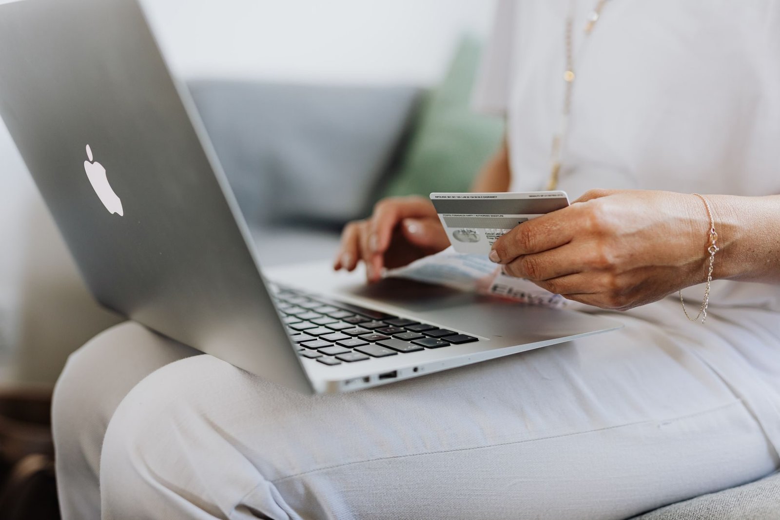 Cláusula penal nos contratos: limites da multa e como negociá-la 1 Close-up of a person holding a credit card while shopping online using a laptop at home.