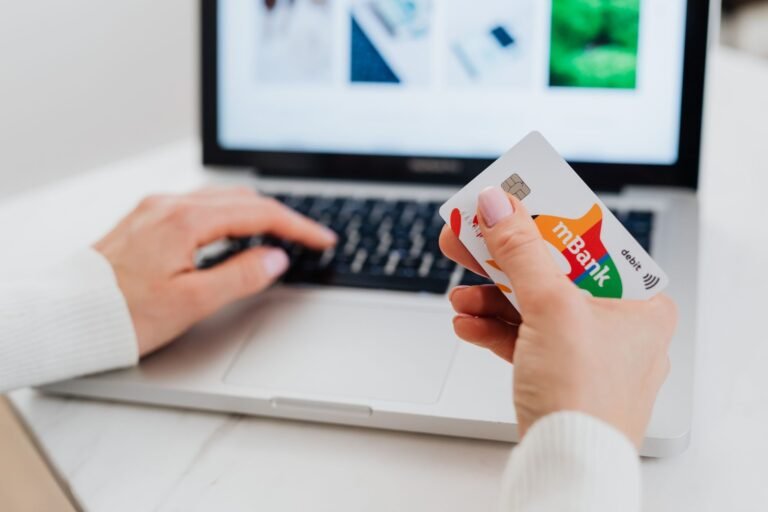 Cobrança abusiva e dívida prescrita: o que o consumidor não precisa pagar 6 Close-up of hands using a laptop and holding a credit card for an online transaction.