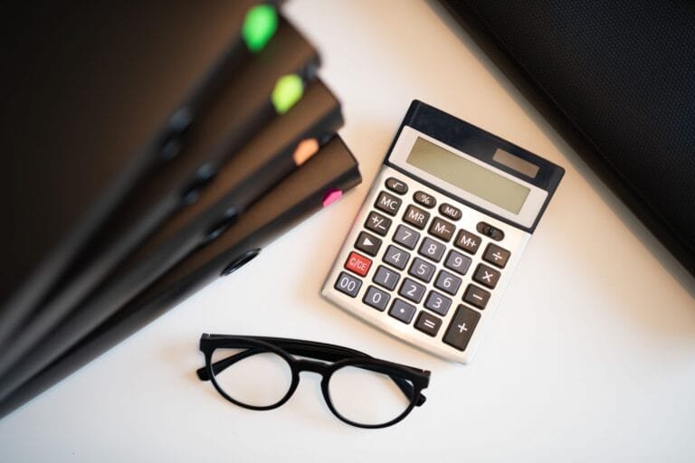 Como aumentar o tempo de contribuição com recolhimentos em atraso 2 Calculator with glasses and folders on an office desk. Perfect for finance and accounting themes.