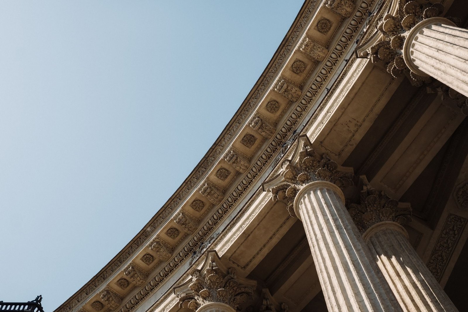 Competencia: como saber em qual cidade e em qual justiça a ação deve correr 1 Detailed low-angle view of classical columns against a clear sky reflecting historical arc