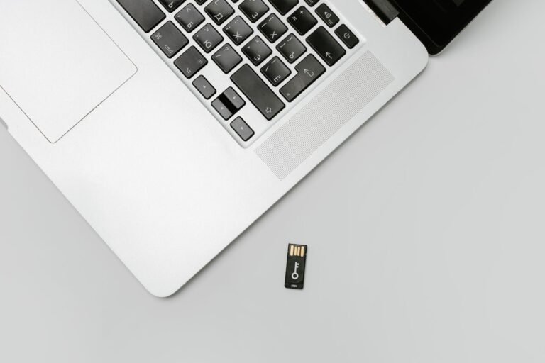 Minimalist flat lay of a laptop with USB drive over a gray background, showcasing technolo