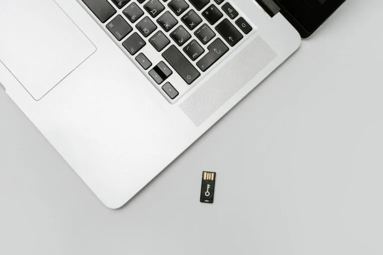 Compra em loja online que sumiu: golpe de e-commerce e como buscar o dinheiro 3 Minimalist flat lay of a laptop with USB drive over a gray background, showcasing technolo