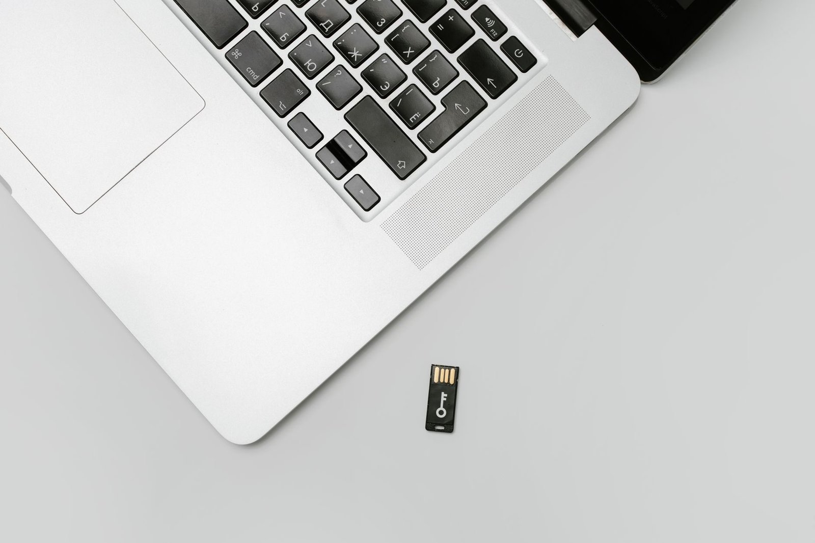 Compra em loja online que sumiu: golpe de e-commerce e como buscar o dinheiro 1 Minimalist flat lay of a laptop with USB drive over a gray background, showcasing technolo