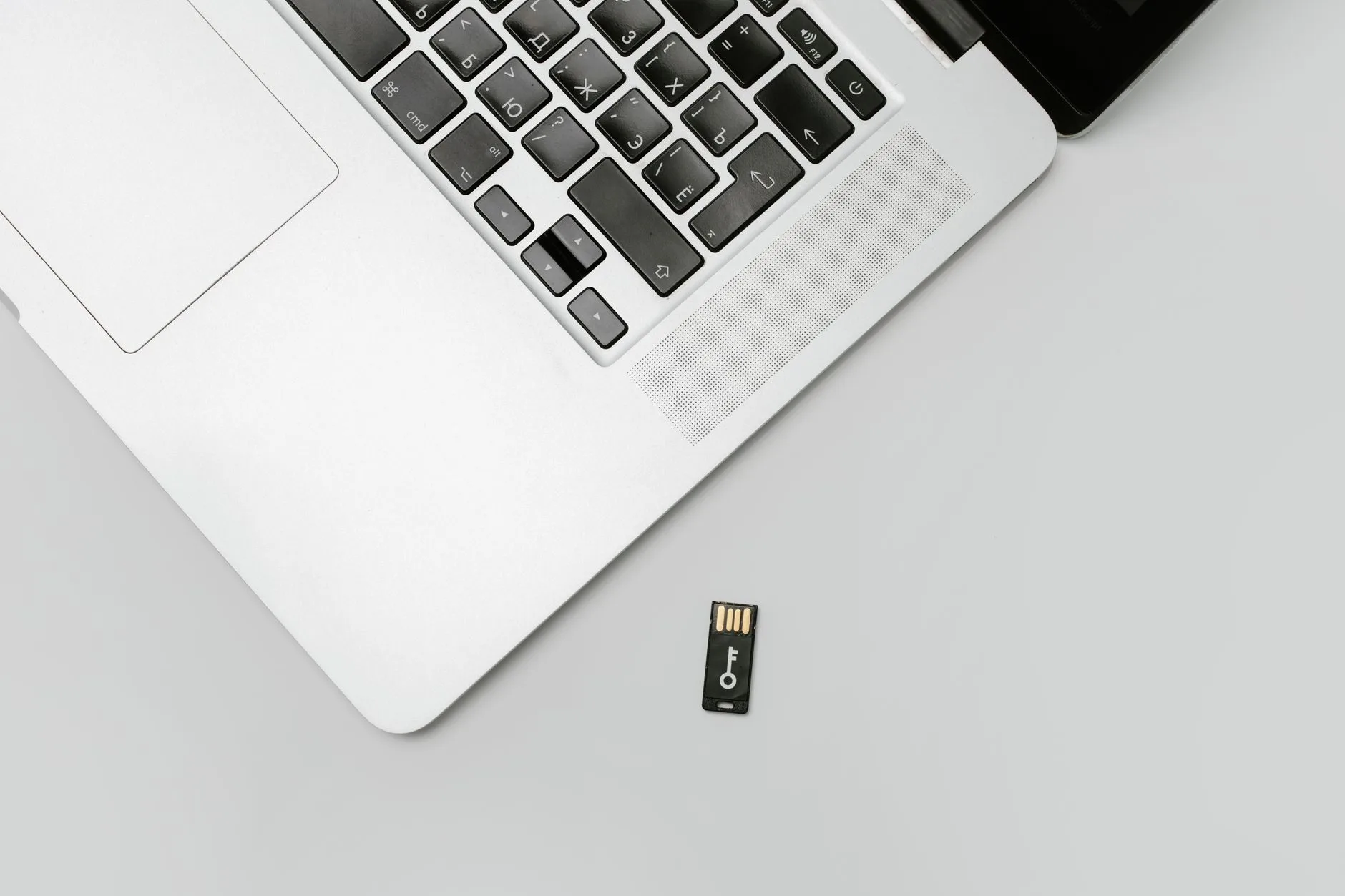 Compra em loja online que sumiu: golpe de e-commerce e como buscar o dinheiro 1 Minimalist flat lay of a laptop with USB drive over a gray background, showcasing technolo