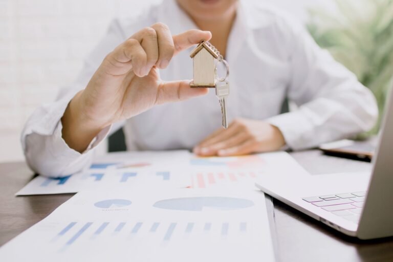 Real estate professional presenting a house model with keys, symbolizing property investme