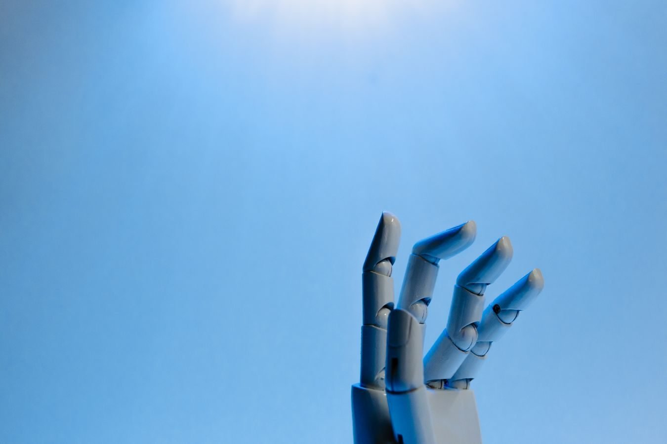 Conteudo gerado por inteligencia artificial tem direito autoral 1 Robotic hand with articulated fingers reaching towards the sky on a blue background.