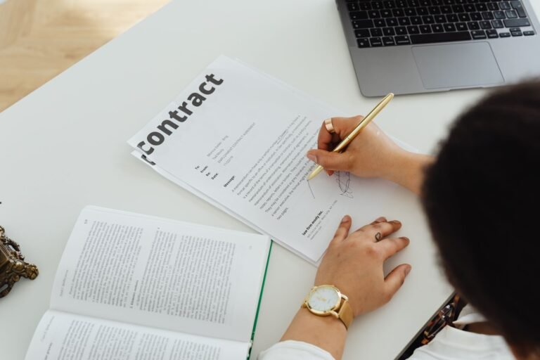 Professional signing a business contract at a modern desk setup for office work.