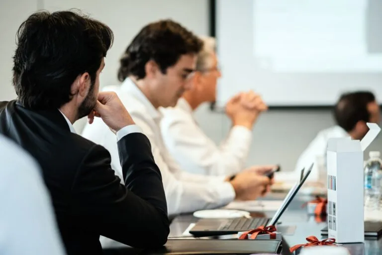 Contrato de franquia: o que avaliar antes de assinar a circular de oferta 7 Corporate professionals in a formal meeting environment, focused on teamwork and collabora