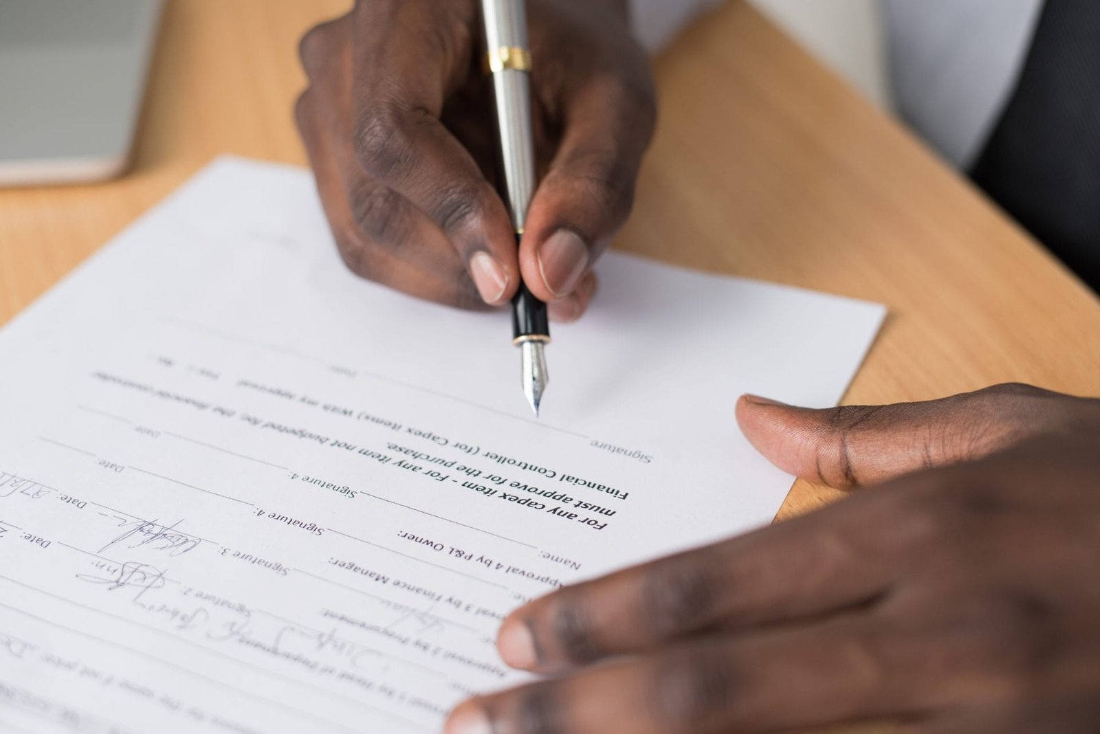 Contrato Social: Cláusulas Essenciais e Estratégicas 1 Close-up of a mans hands signing a formal document indoors.