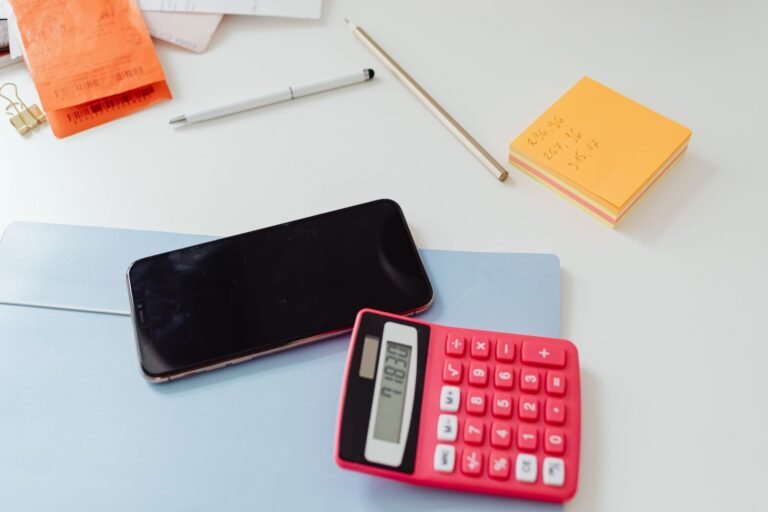 Contribuicoes previdenciarias da empresa: como reduzir riscos de autuacao 6 An organized office desk featuring a calculator, smartphone, and sticky notes on a white s