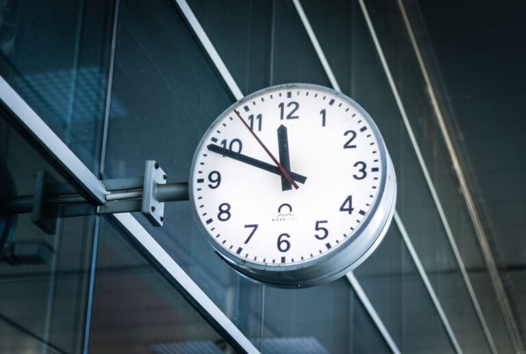 A large white analog clock mounted on the glass wall of a modern building in Osijek, Croat