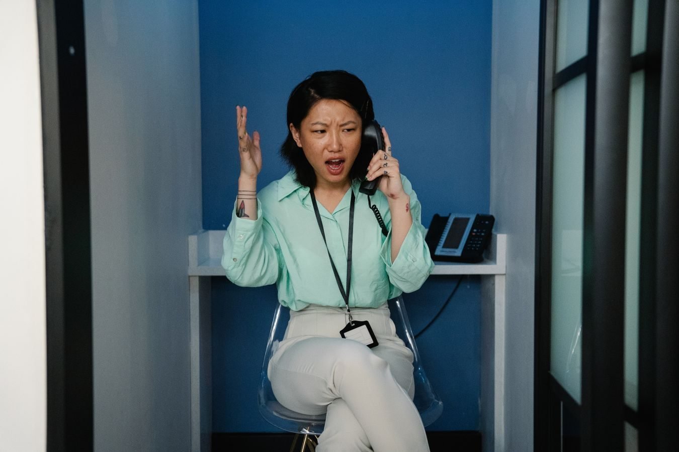 Dano moral: quando o aborrecimento realmente gera indenizacao 1 An east Asian woman expressing frustration during a phone call at the workplace.