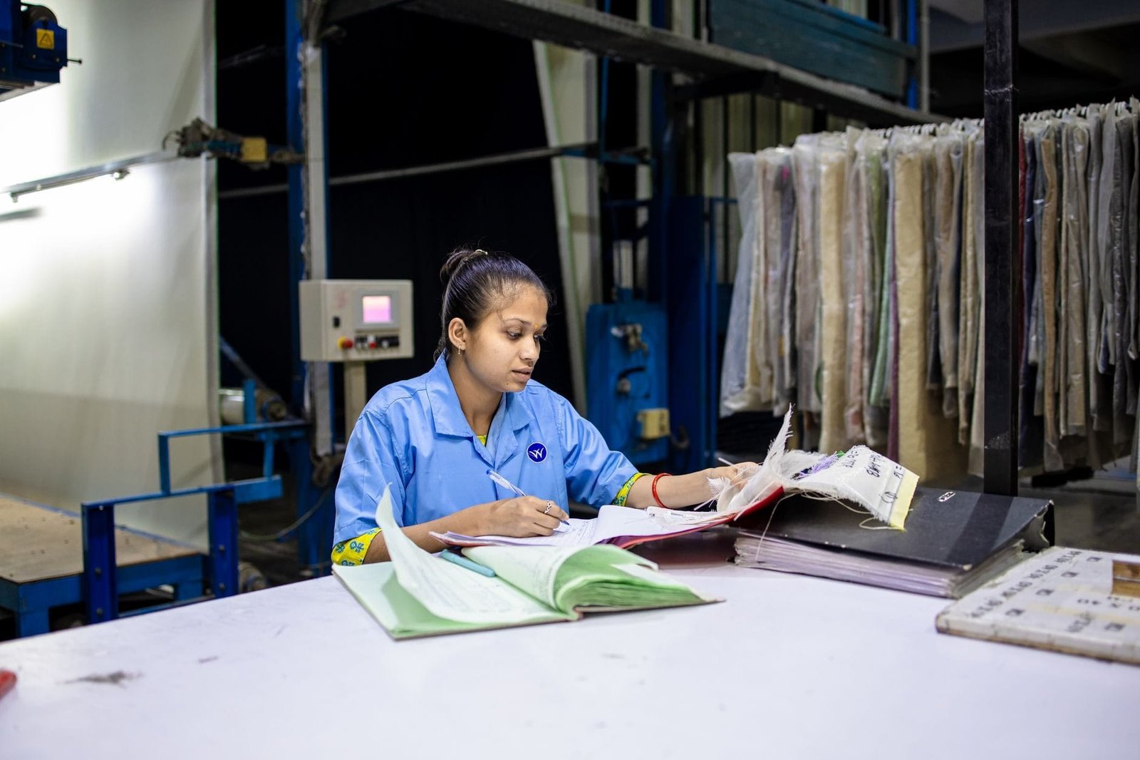 Descarte de contribuições baixas: e possível excluir salários menores 1 A female textile worker in a factory reviews documents at a workstation.