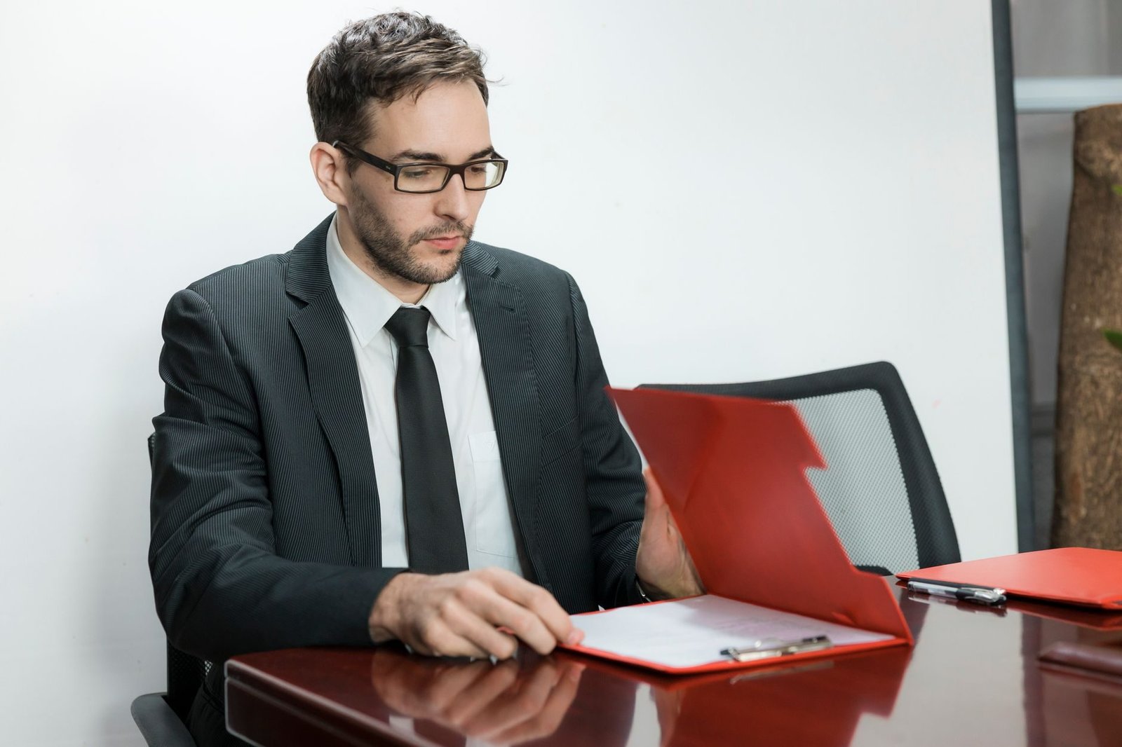 Professional man in suit reviewing papers at office desk with focus and determination.