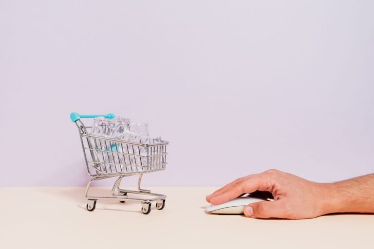 Conceptual image of a hand on a mouse next to a miniature shopping cart filled with ice cu
