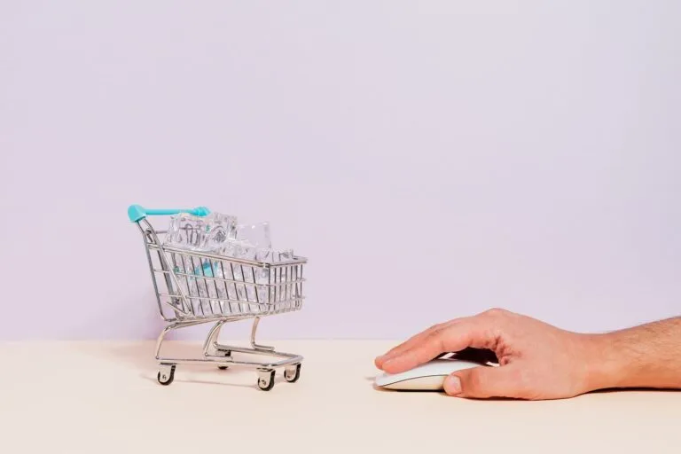 Direito de arrependimento nas compras online: prazos, devolução e reembolso 6 Conceptual image of a hand on a mouse next to a miniature shopping cart filled with ice cu